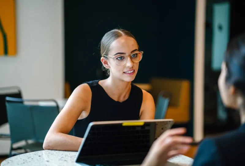 Two people talking in a bright meeting space.