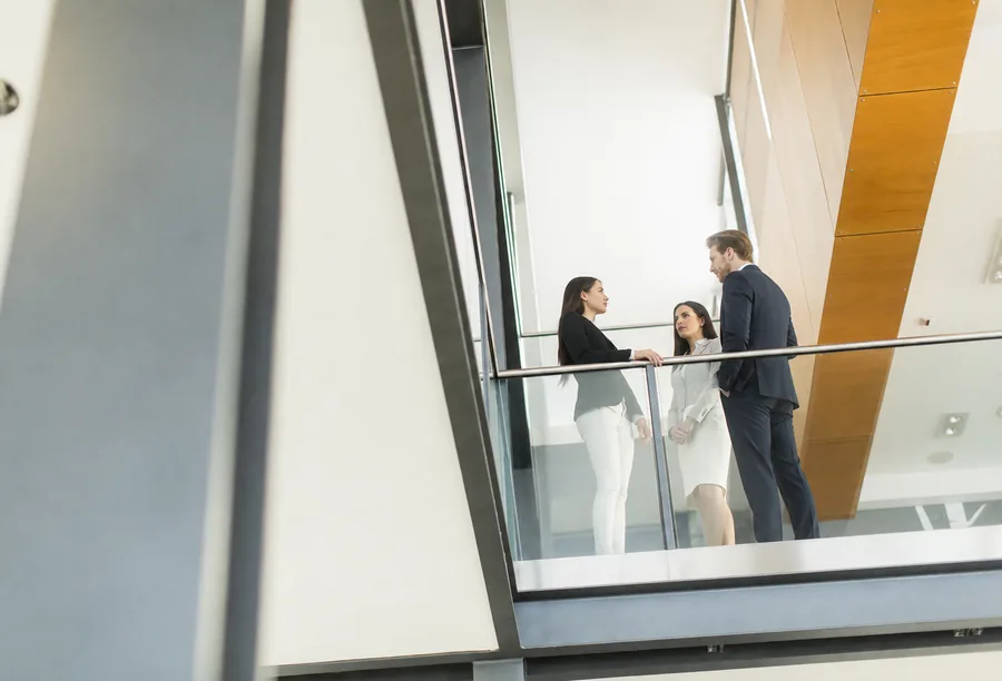 Professionals talking in a bright office atrium.
